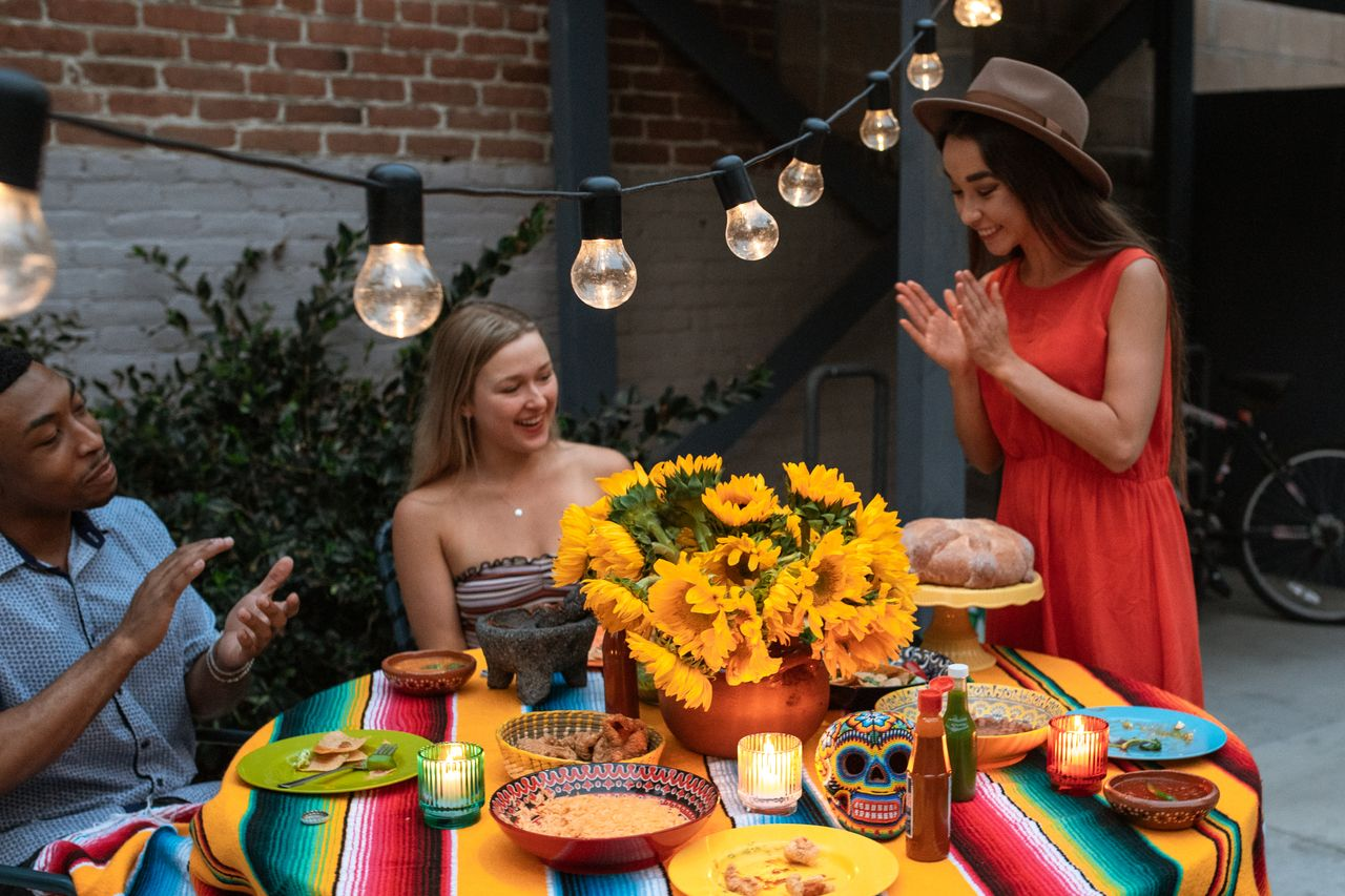 A joyful evening gathering with friends enjoying a colorful table setting and vibrant sunflowers.